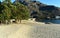 Beach with mountain and trees. Golden sand, bridge and seagulls, sunset light. Ezaro, Galicia, Spain. Sunny day, blue sky.