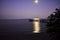 The beach at night and the moonlit path passing by the pier