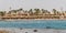 Beach with palms tree in Hurghada, tourists with sunbeds and umbrellas on the hot summer day