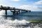 Beach pier in the sea waves against a blue sky on the Baltic Sea