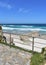 Beach promenade with handrail. White sand, rocks and turquoise sea with wild waves and blue sky. Viveiro, Lugo, Galicia, Spain.