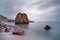 Beach with reddish stone blocks, water and cloud movement