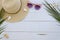 Beach relaxation board presentation with summer hat, sun glasses, palm leaves and sea shels on white planks background