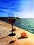 Beach restaurant ,summer seaside leisure  glass of red wine on stone and seashells nature panorama blue sky and sea water  reflect