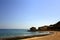 Beach with rocks, blue sea, bathers and flock of flying birds