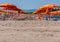 Beach with rows of orange umbrellas.