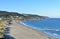 Beach with sand dunes and rocks. Blue sea with small waves, sunny day, clear sky. Morning light, Galicia, Coruna, Spain.