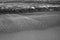 Beach sand with the foam of the surf Atlantic. Black and white photo.