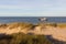 Beach with sand, marram grass and a ship in the background