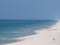 Beach sand ocean waves pier clouds sky