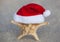 On the beach, the sand is a starfish wearing a Santa Claus hat. Celebrating the New Year and Christmas in the Ocean Sea.