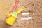 Beach sand with toys for the baby, water, the word holi stay in colored letters