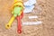 Beach sand with toys for the baby, water, the word holi stay in colored letters