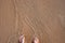 Beach sand and woman feet in sea wave top view. Relaxing photo of sandy beach and clean seawater. Girl feet in sandals
