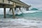 Beach scene with wooden fishing pier and waves in Atlantic Ocean in Florida