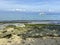 Beach scenery with stone plates and sand, blue sea. Ship sailing background sky