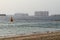 The beach by the sea, in the distance construction and residential high-rise buildings of the Jumeirah palm tree during sunset.