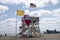 Beach shoreline with lifeguard tower with flags rescue boards sun umbrella