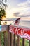 Beach sign on wooden boardwalk leading to the water. Canadian flag in the background