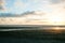 Beach in silhouette as sunsets on distant horizon over ocean