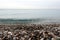 Beach with small smooth pebble and clean calm transparent sea till skyline