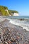 Beach with stones and chalk cliffs in distance.