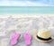 Beach summer holiday background. Flip flops and hat on sand near ocean. Summertime accessories on seaside. Tropical vacation