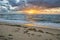 Beach sunrise with seaweed and sea debris in sand