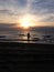 Beach sunset reflecting over dark waves with slim teenage girl