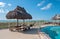 Beach table with hay parasol next to a swimming pool