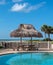 Beach table with hay parasol next to a swimming pool