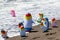 Beach toy background. Selective focus on a group of eight colorful inflatable rubber penguin toys at a sandy sunny beach. Space