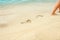 A Beach travel - woman relaxing walking on a sandy beach leaving footprints in the sand. Close up detail of female feet on golden