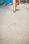 A Beach travel - woman relaxing walking on a sandy beach leaving footprints in the sand. Close up detail of female feet on golden