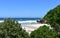 Beach with trees, turquoise sea with waves, cliff and blue sky. Viveiro, Lugo, Galicia, Spain.