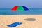 Beach umbrella and towel on a deserted beach.