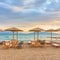 Beach with umbrellas by the sea at sunset