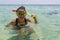 Beach vacation fun woman wearing a snorkel scuba mask making a goofy face while swimming in ocean water. Closeup