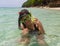 Beach vacation fun woman wearing a snorkel scuba mask making a goofy face while swimming in ocean water. Closeup