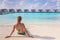 Beach vacation holidays with woman sun bathing on white sand at luxurious hotel resort in Maldives with overwater villas,