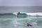 Beach view with professional surfers and Standup Paddleboarding doing extreme maneuvers in sea with waves