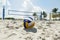 A beach volleyball net on a sunny beach, with palm trees