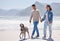 Beach, walking and couple with dog by ocean for freedom, adventure and bonding together in nature. Happy pet, excited