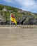 Beach warning flag standing on the sands of St.Agnes beach cove