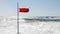 Beach warning red flag splashing on wind.