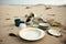 beach with waste from tourist hotels and restaurants, cups, plates and plastic cutlery strewn across the sand