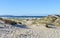 Beach with waves breaking, grass in sand dunes and blue sky. Arteixo, Coruna, Galicia, Spain.