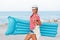 Beach woman happy and wearing beach hat with blue mattress having summer fun during travel holidays vacation