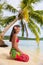 Beach woman relaxing on Bora Bora Tahiti island under the sun wearing polynesian skirt and monoi flower with palm tree