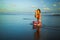 Beach yoga. Attractive woman practicing Gomukhasana Garudasana. Cow Face Pose with Eagle Arms. Water reflection. Slim fit body.